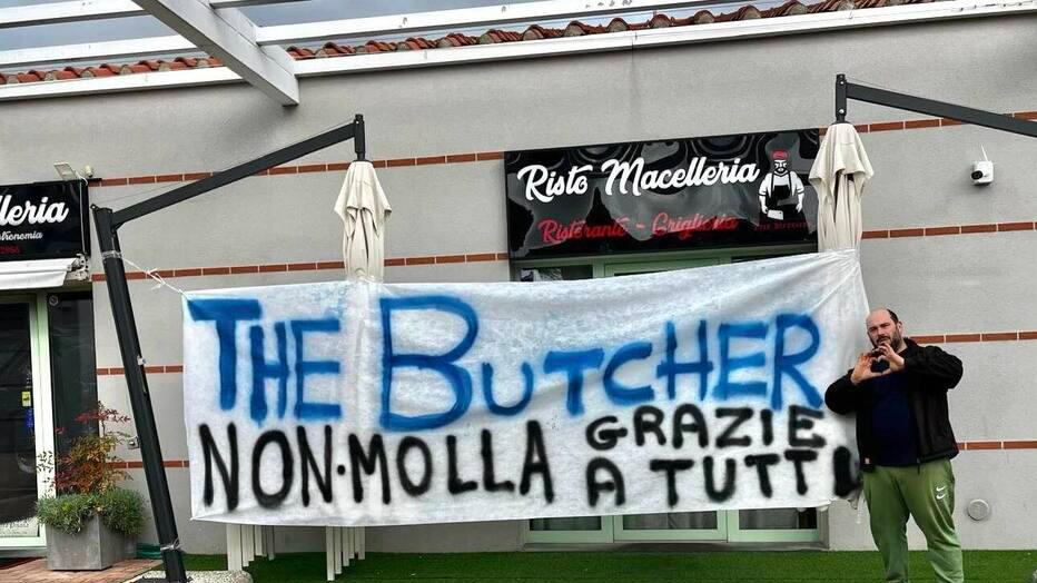 Il titolare e lo striscione fuori dal locale