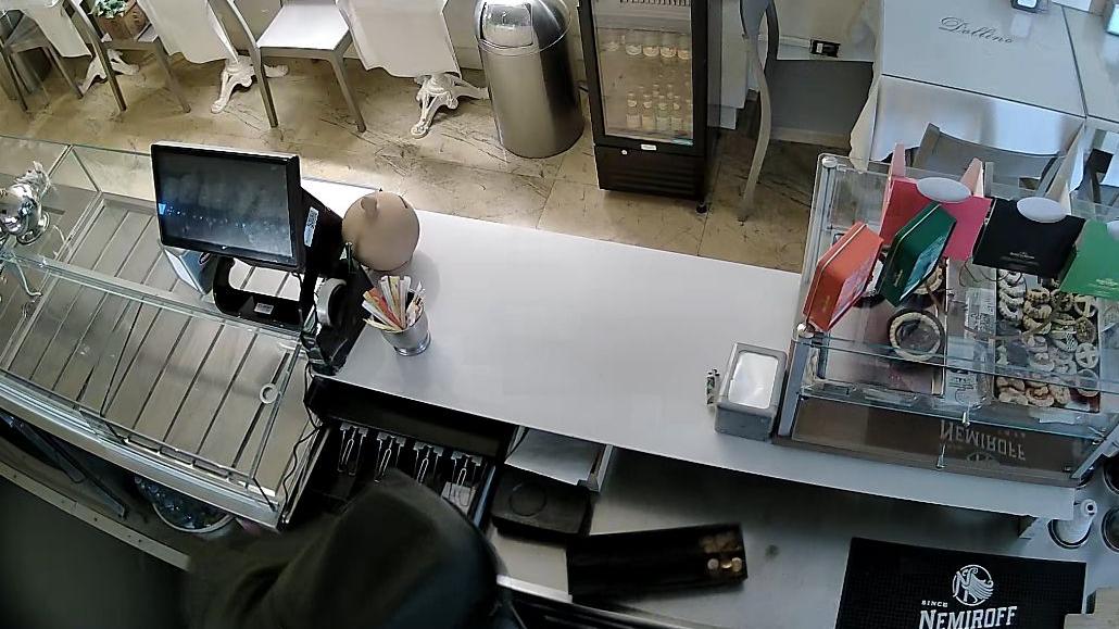 Il ladro mentre armeggia con la cassa in un frame delle telecamere di videosorveglianza del locale 