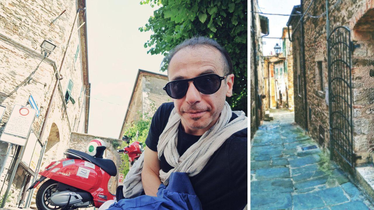 
	Il giornalista Lorenzo Lombardi con la Vespa e un vicolo caratteristico del borgo di Montemerano


