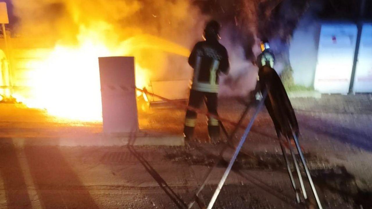 Un pompiere impegnato a spegnere un cassonetto a fuoco (foto d’archivio)