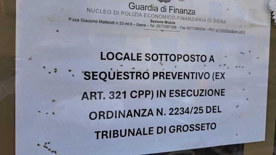 L’ordinanza di sequestro preventivo sul vetro del mini-market. Come si può vedere decine di moscerini sono ammassati tra la vetrata e il cartello