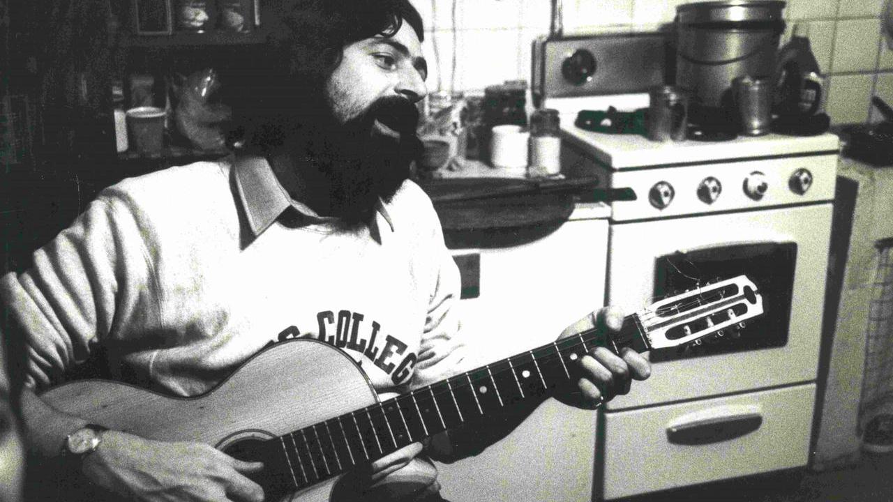 Un giovane Guccini alla chitarra in cucina