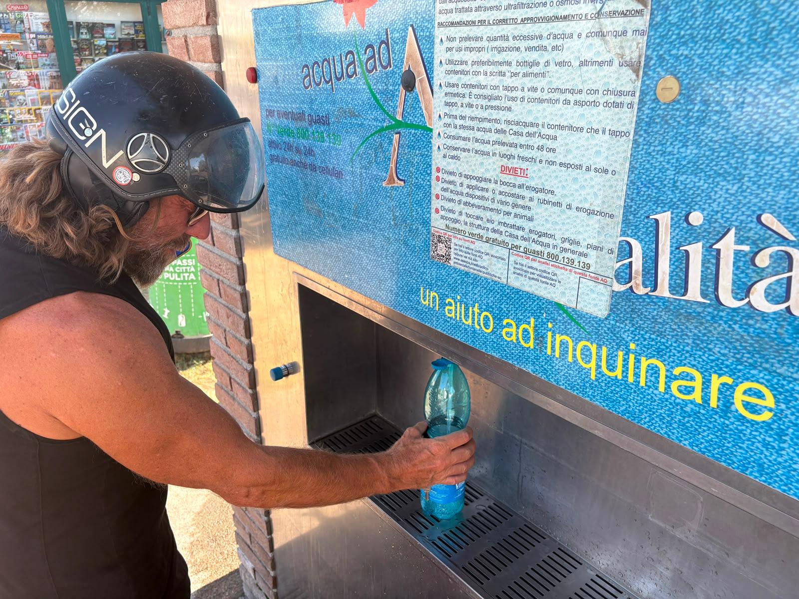 Un livornese mentre si disseta a un fontanello gratuito di Asa (foto Stick)