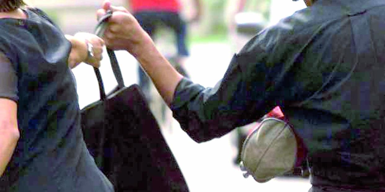 La affiancano in bicicletta e in due tentano di scipparle la borsa: lei reagisce e finisce a terra