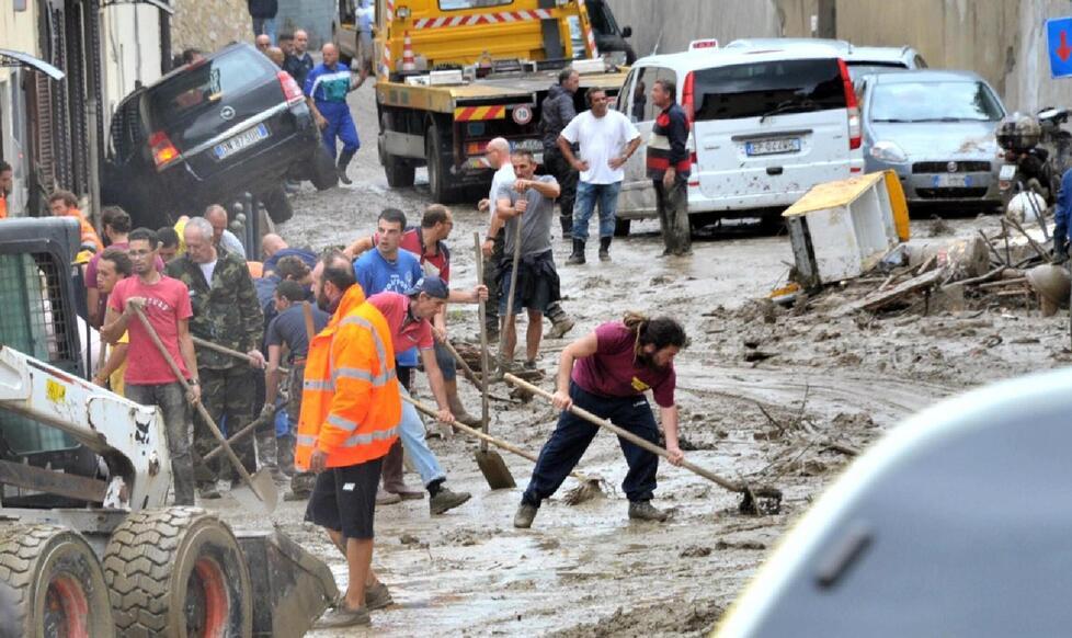 Volontari mentre spalano il fango dopo l'alluvione (foto Pentafoto / Archivio Tirreno)