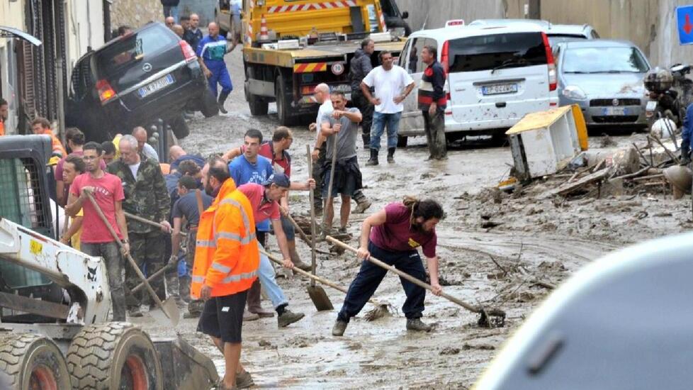 Volontari mentre spalano il fango dopo l'alluvione (foto Pentafoto / Archivio Tirreno)