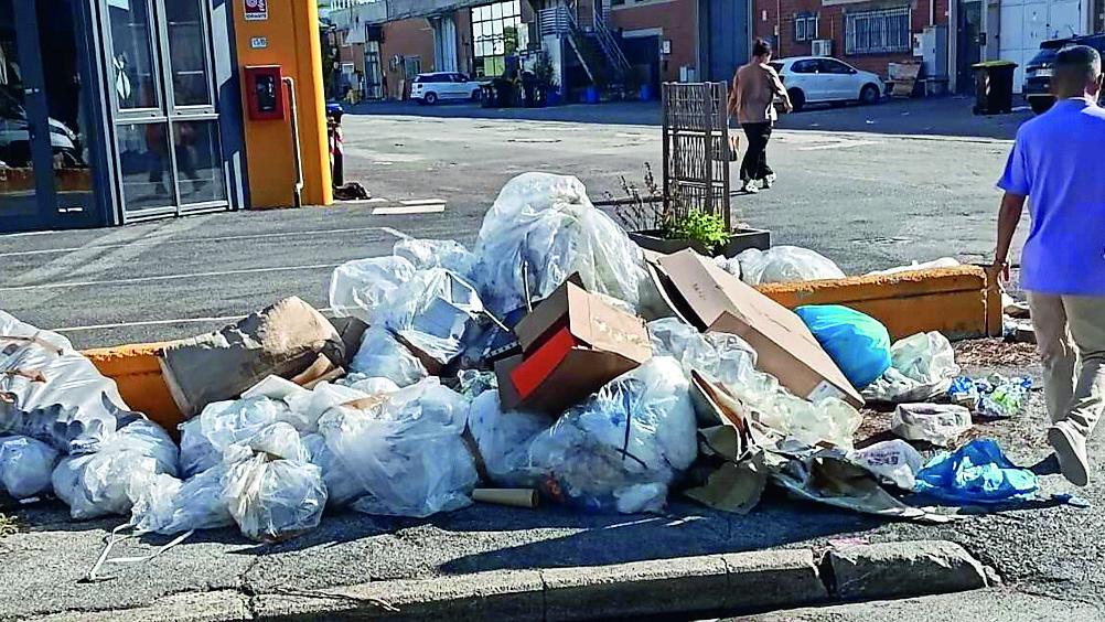 Un marciapiede invaso dai rifiuti al Macrolotto (foto Giovanni Tarducci)