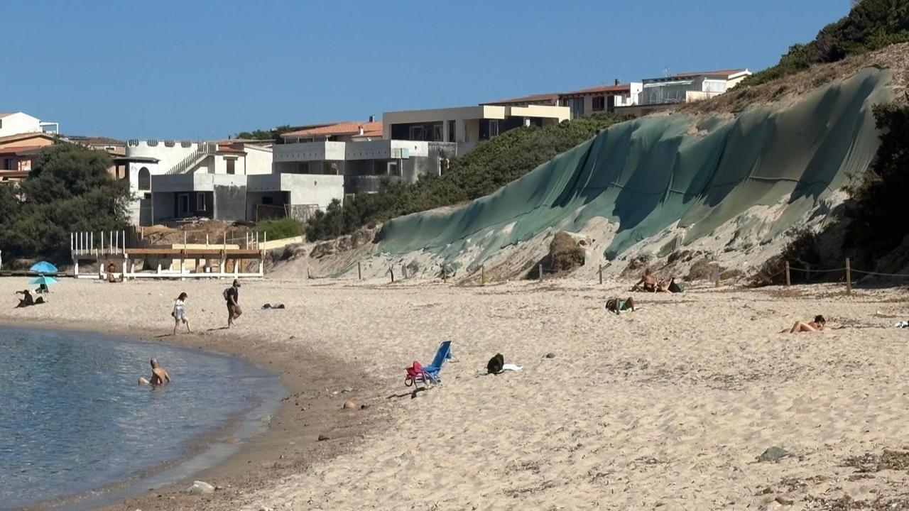 Montagna di rifiuti a Isola Rossa, c’è ancora il telone dietro la spiaggia. I bagnanti: «Non ne sappiamo nulla» – La polemica dell’estate