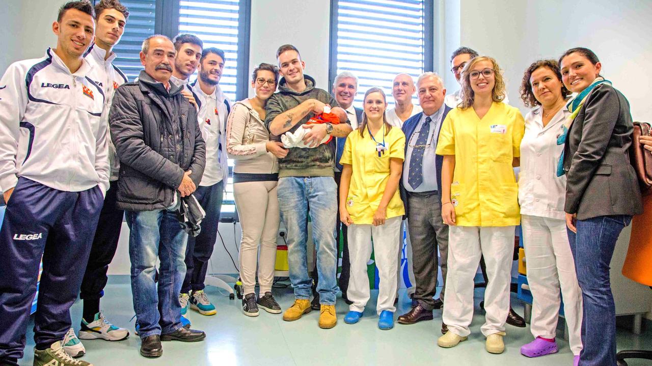 Il piccolo Emiliano con la sua magluetta arancione insieme a genitori, giocatori e dirigenti della Pistoiese