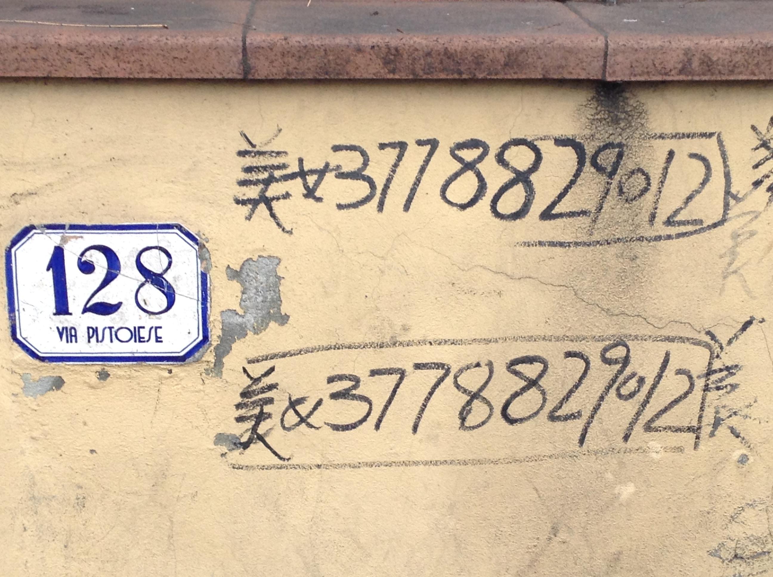 Numeri di telefono scritti su un muro di via Pistoiese