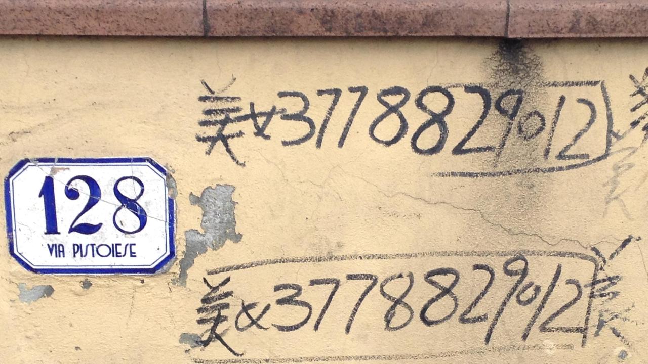 Numeri di telefono scritti su un muro di via Pistoiese