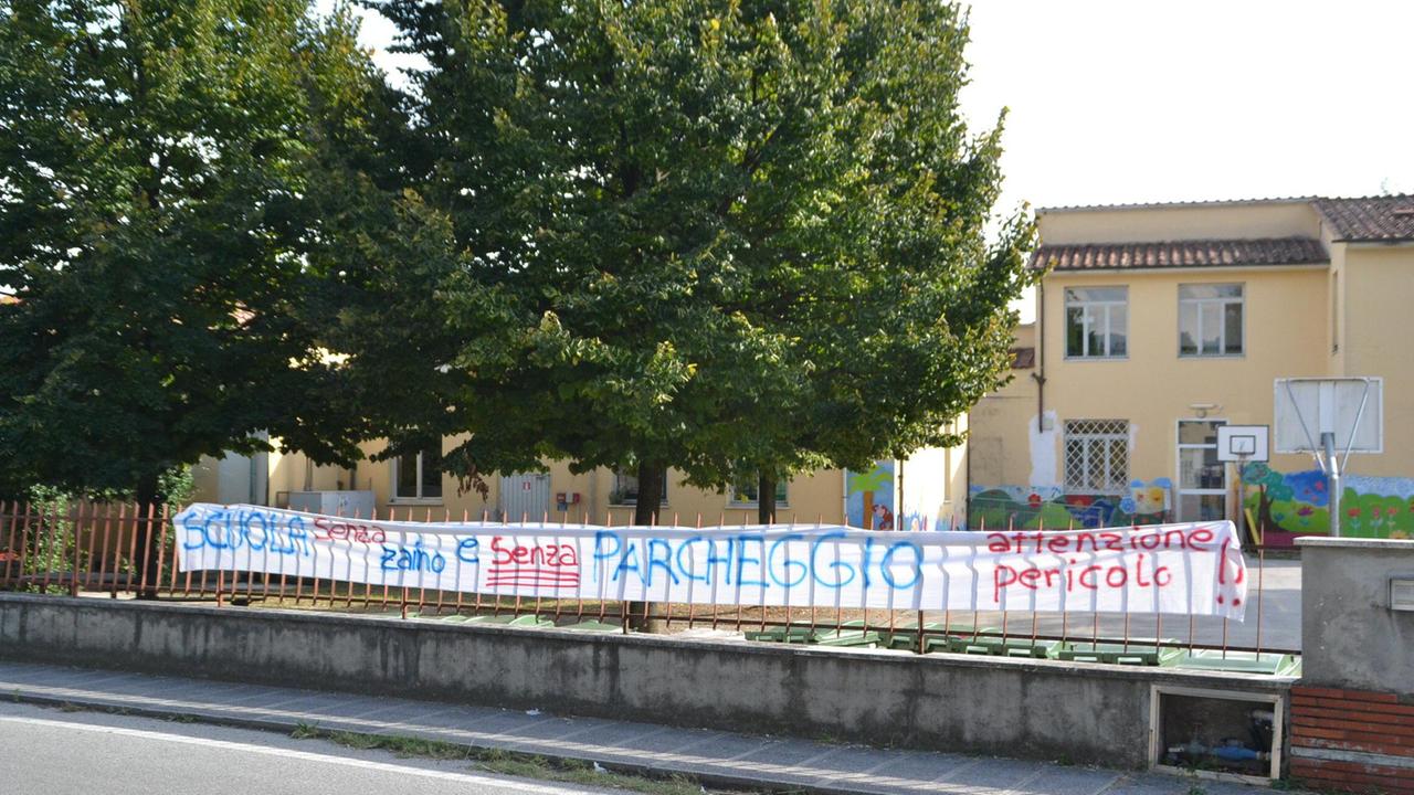 Uno striscione appeso alla scuola per chiedere il parcheggio