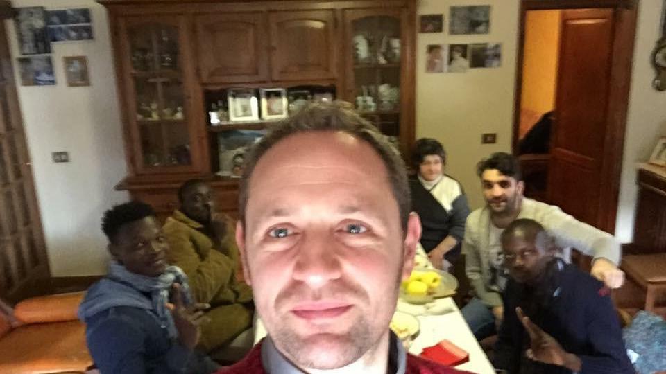 Don Alessandro Carmignani insieme ad alcuni profughi ospitati a tavola da una famiglia di Marliana