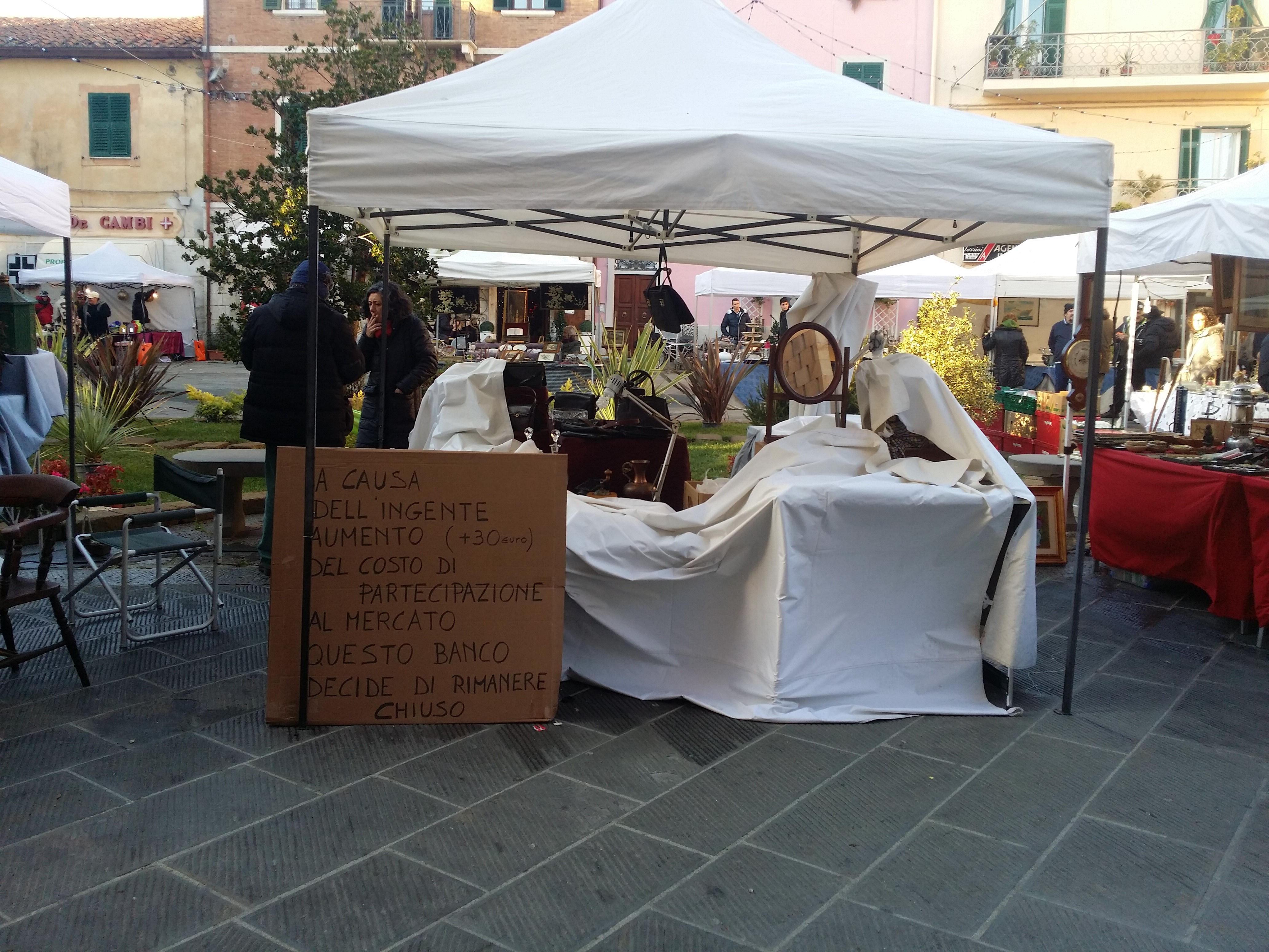 Il banco chiuso al mercatino dell'antiquariato a Orbetello e il cartello di protesta