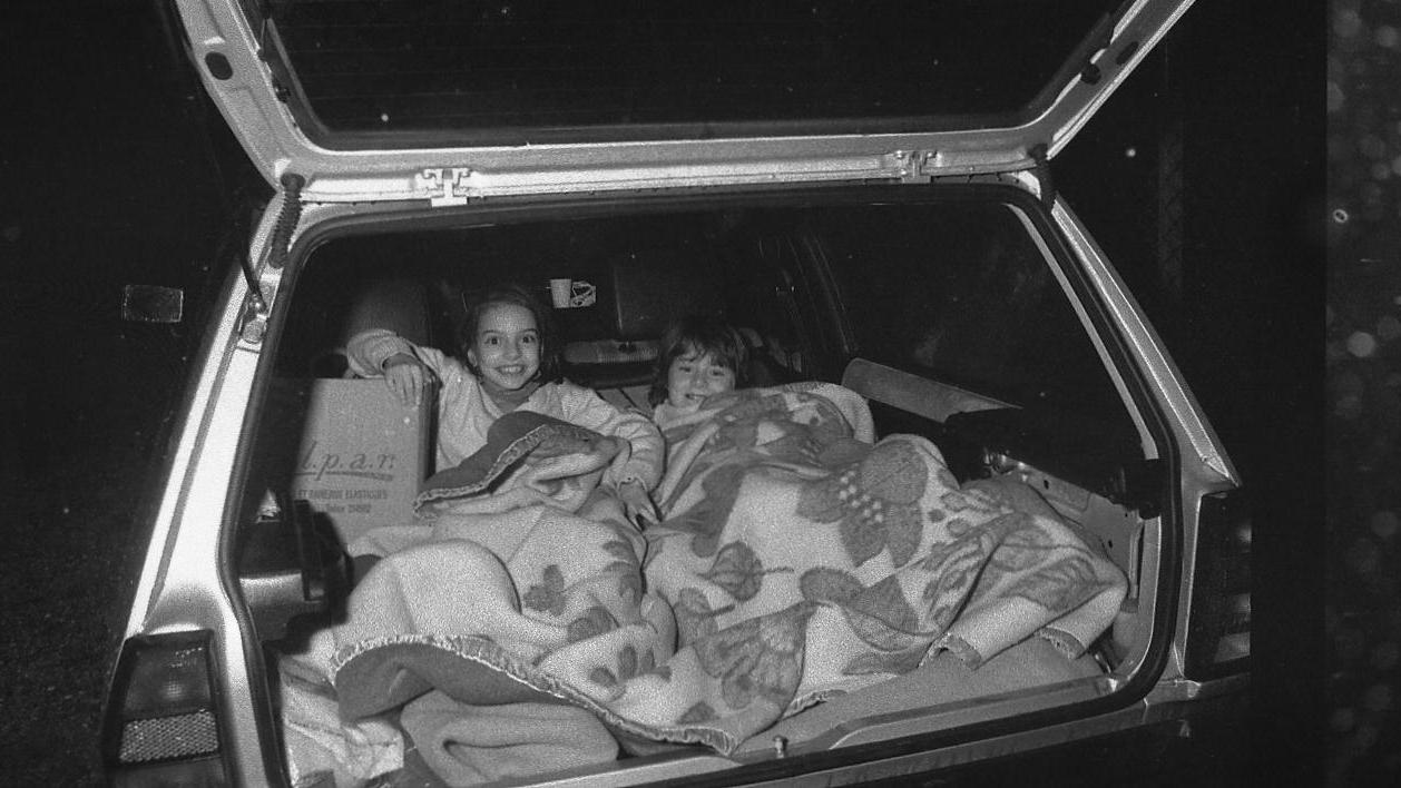 Una delle foto simbolo: una famiglia dorme nel bagagliaio di un'auto (Foto Vip)