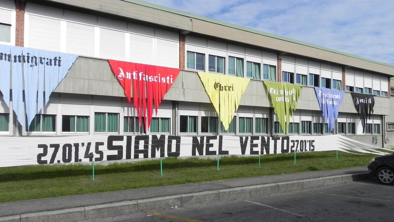 Gli striscioni a forma di triangolo appesi alla scuola Don Milani: quello rosso è stato strappato durante la notte