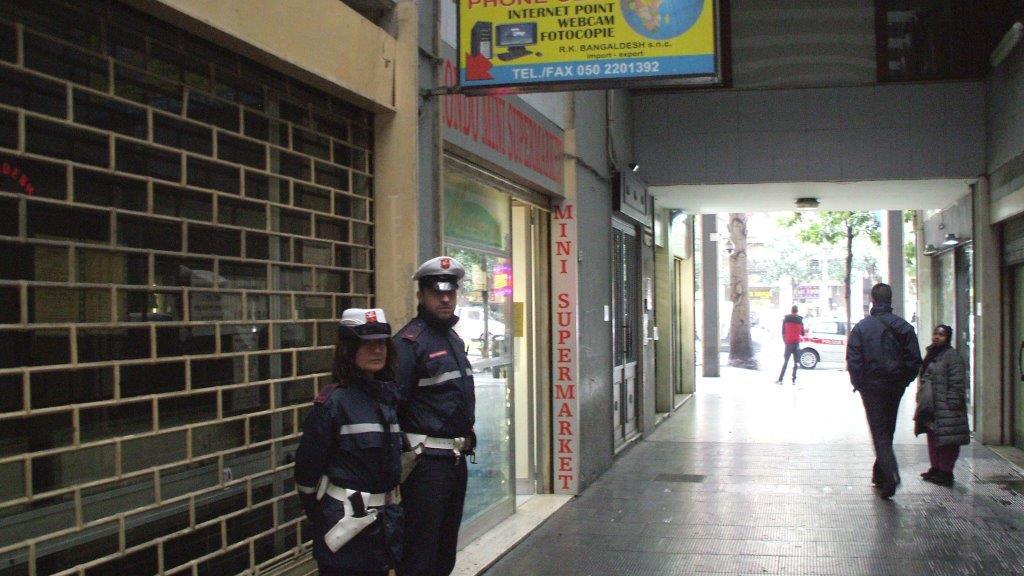 Agenti della polizia municipale davanti al phone center chiuso vicino alla stazione