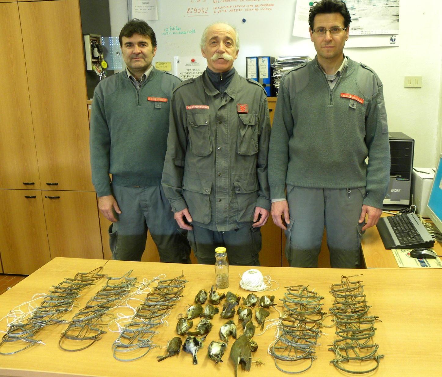 Gli agenti della polizia provinciale con le tagliole e gli uccelli sequestrati al bracconiere