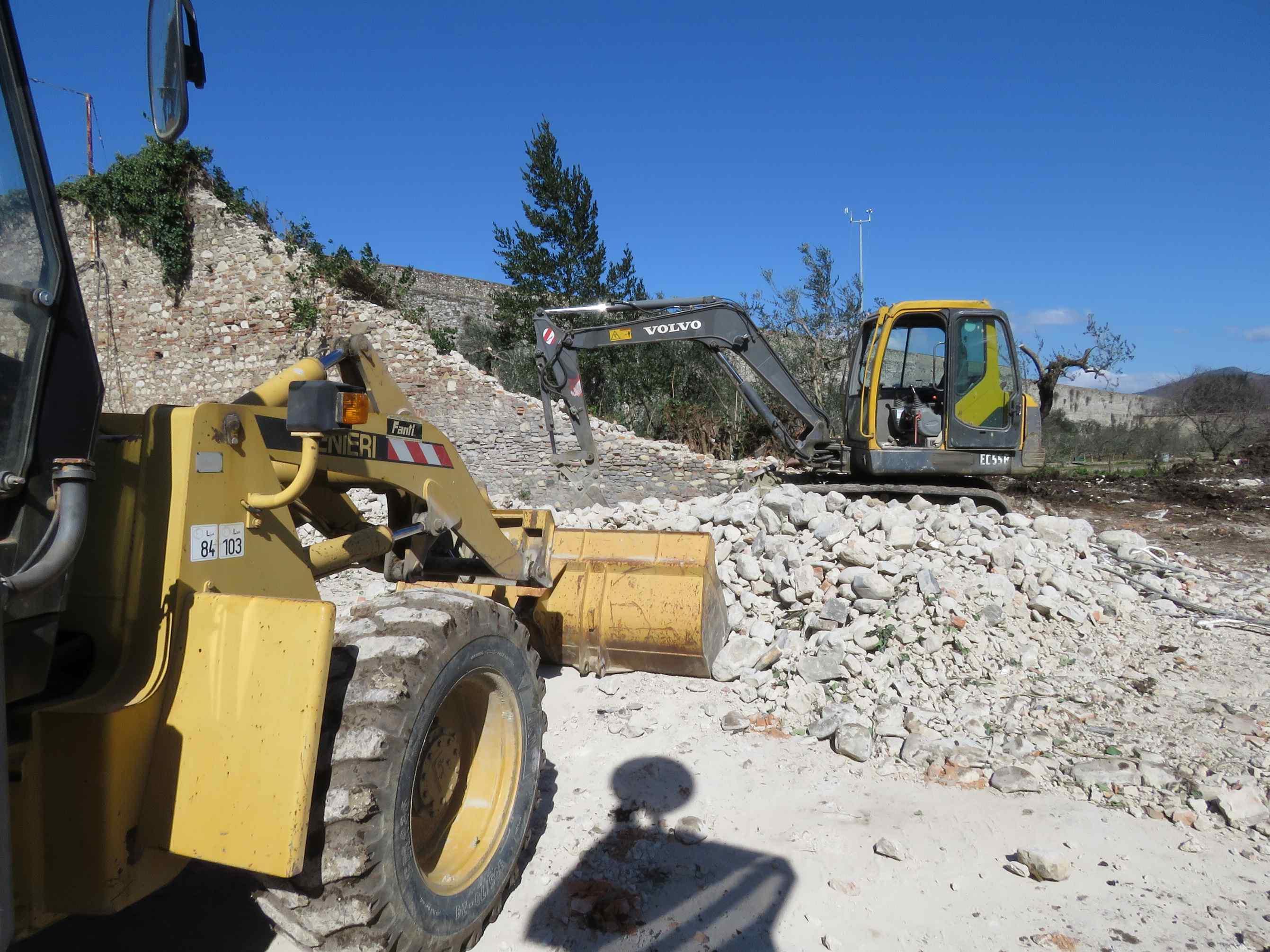 Ruspe in azione per raccogliere le pietre delle mura (foto Batavia)