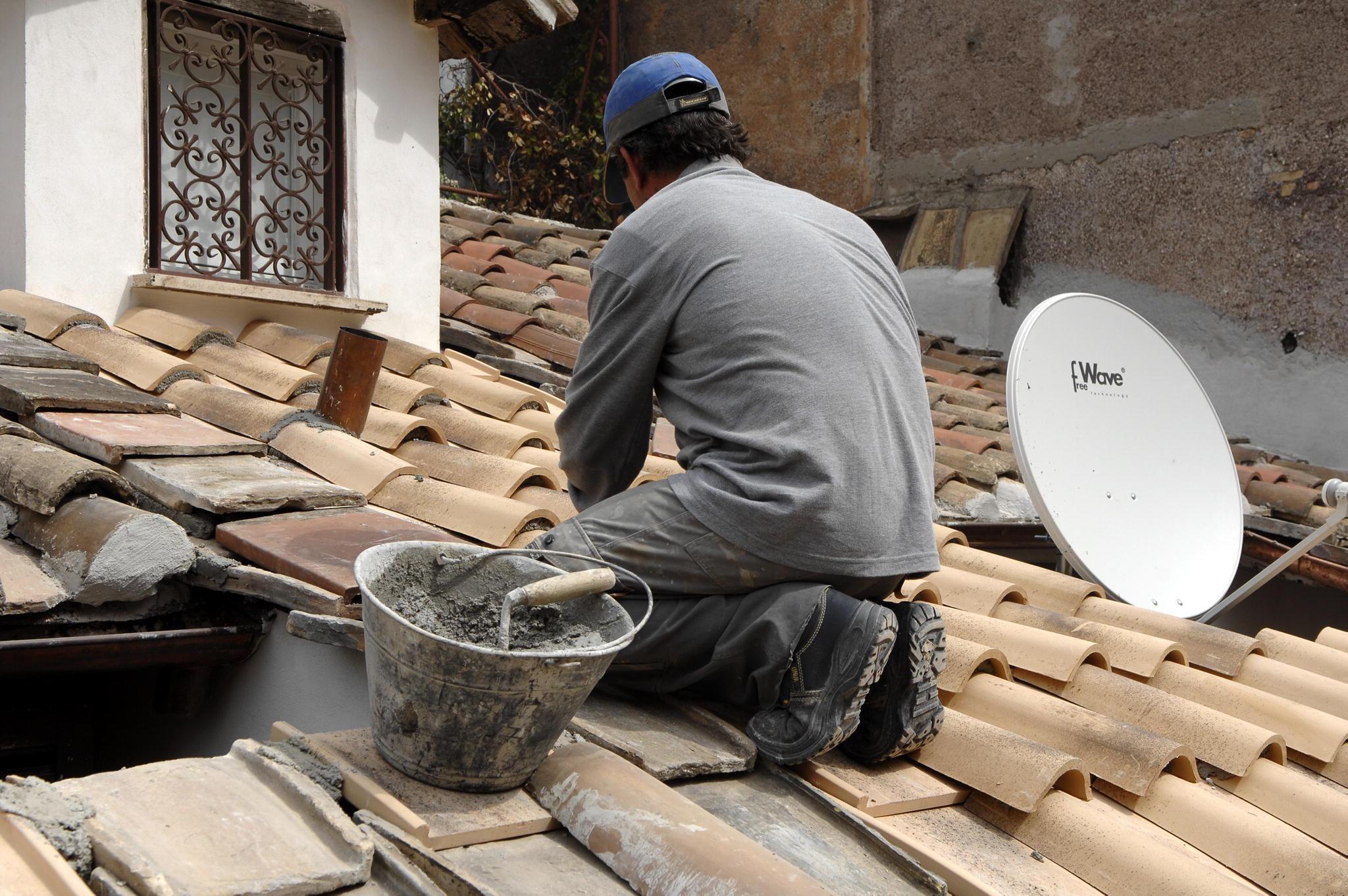 Un operaio impegnato nella riparazione di un tetto