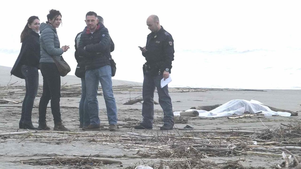 Il cadavere sotto il telo sulla spiaggia e gli investigatori della polizia