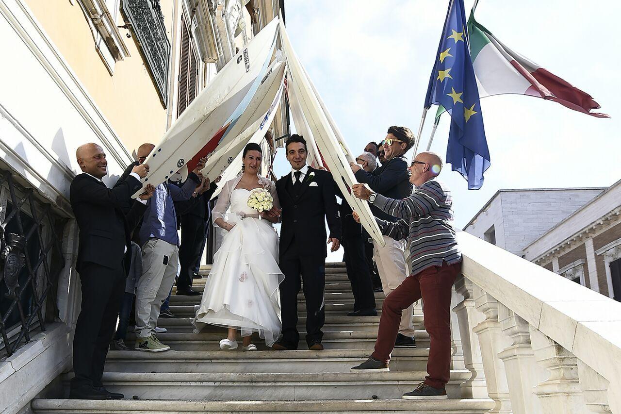 Debora e Luca sfilano sotto l'arco di tavole da surf all'uscita dal Comune (foto di Diego Giusti)