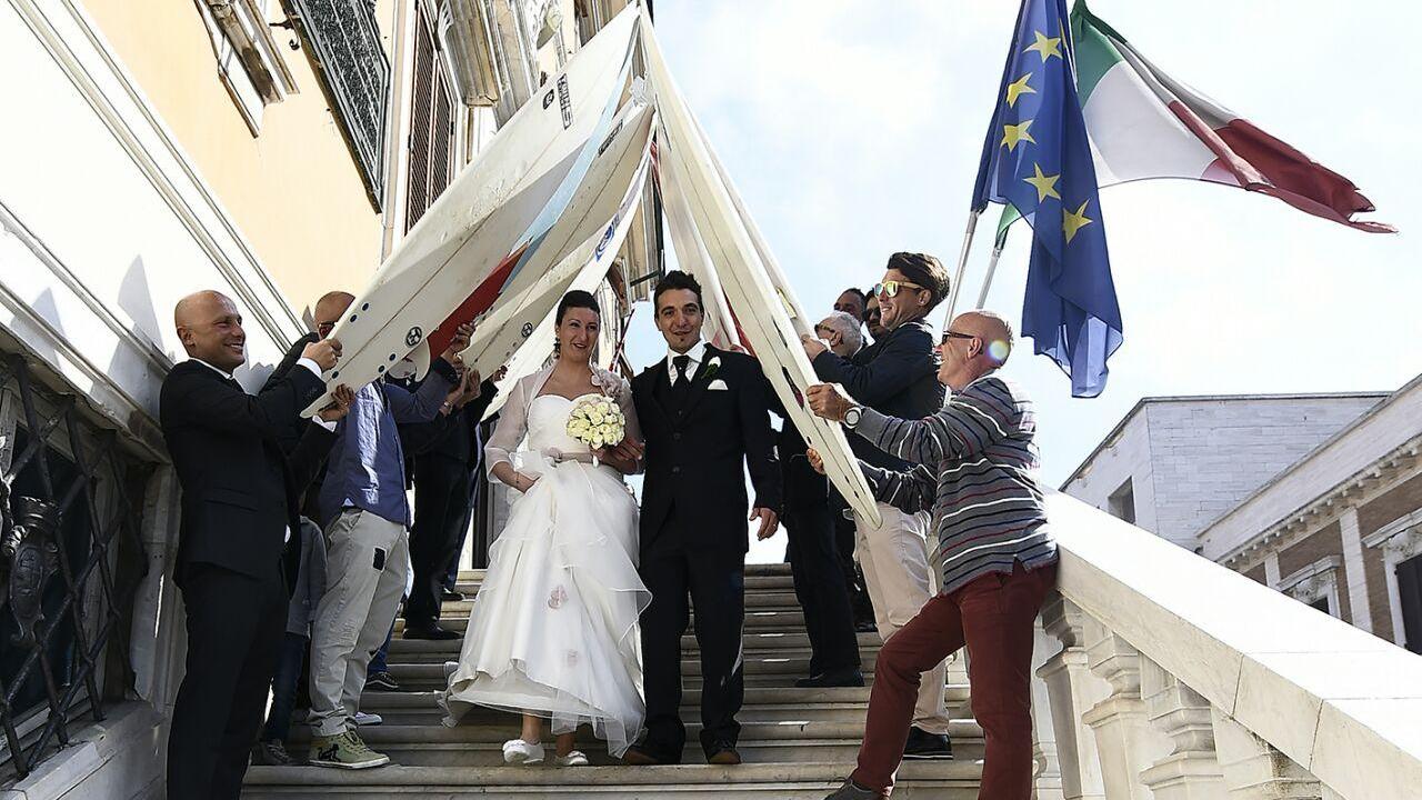 Debora e Luca sfilano sotto l'arco di tavole da surf all'uscita dal Comune (foto di Diego Giusti)