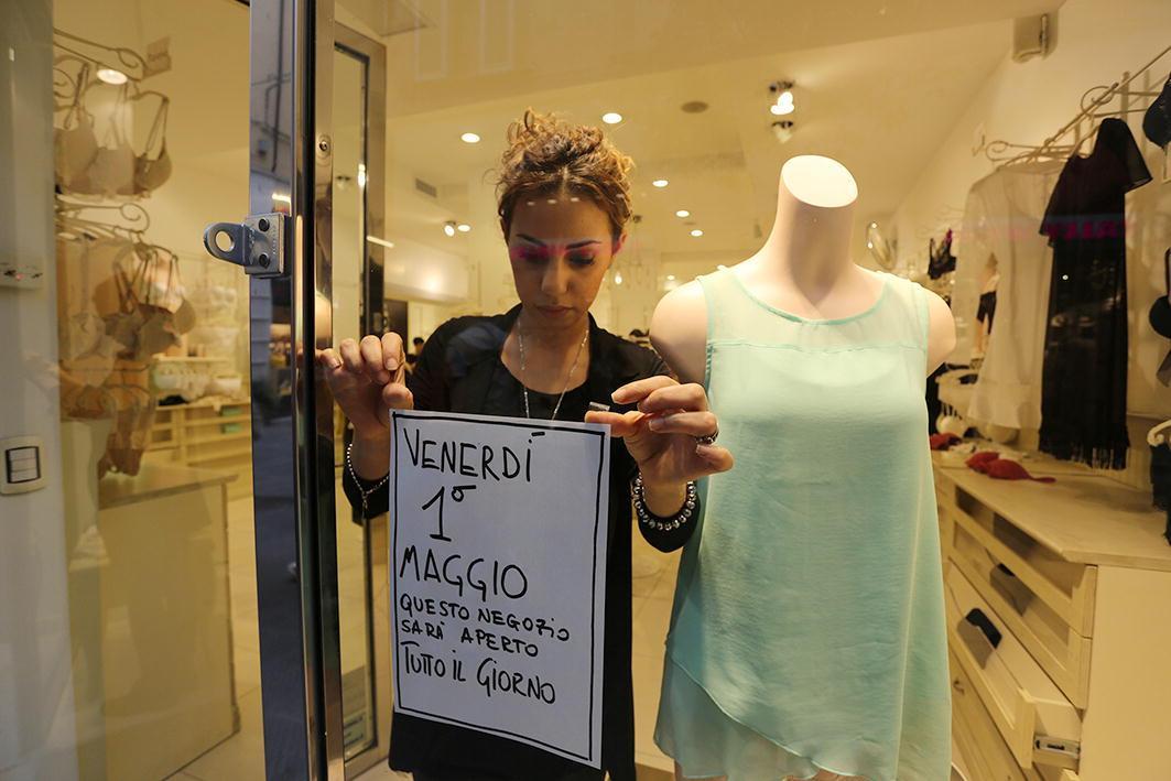 Una commessa del negozio Intimissimi che appende il cartello di apertura 