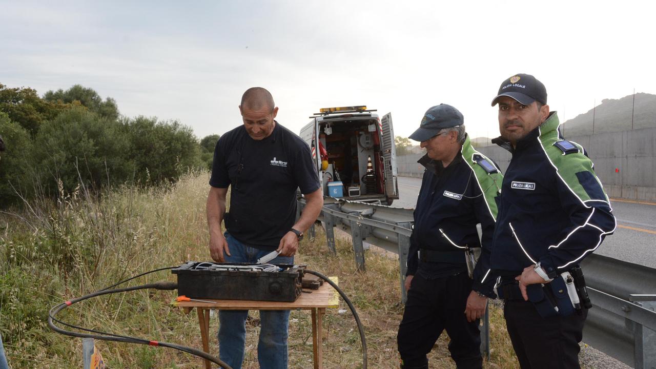Un tecnico Telecom osserva insieme a due agenti della polizia locale il cavo tranciato