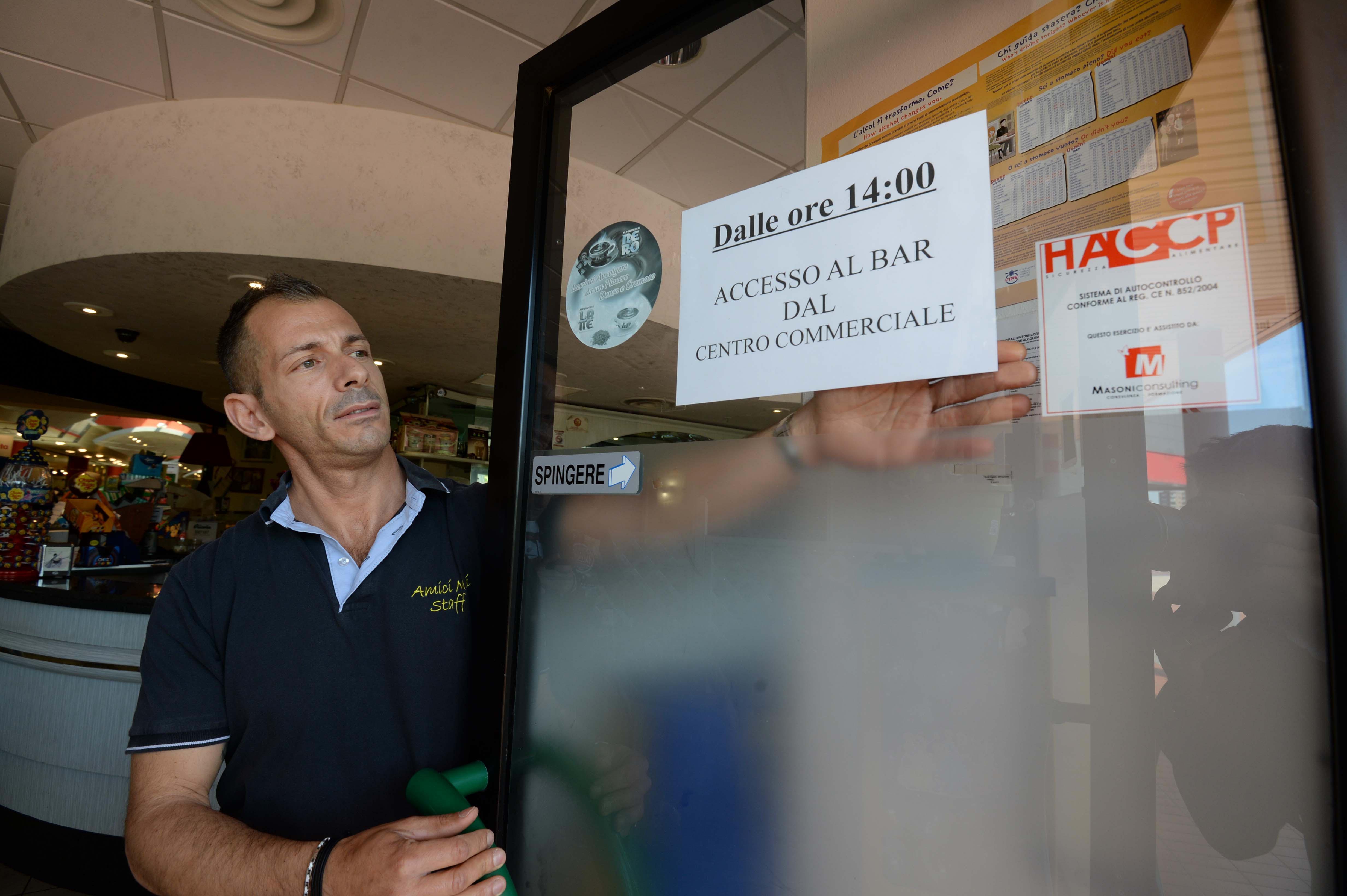 Il gestore del bar Maurizio Vigerelli appone il cartello al suo locale (foto Silvi)