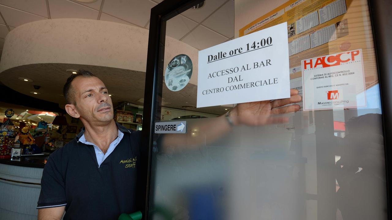 Il gestore del bar Maurizio Vigerelli appone il cartello al suo locale (foto Silvi)