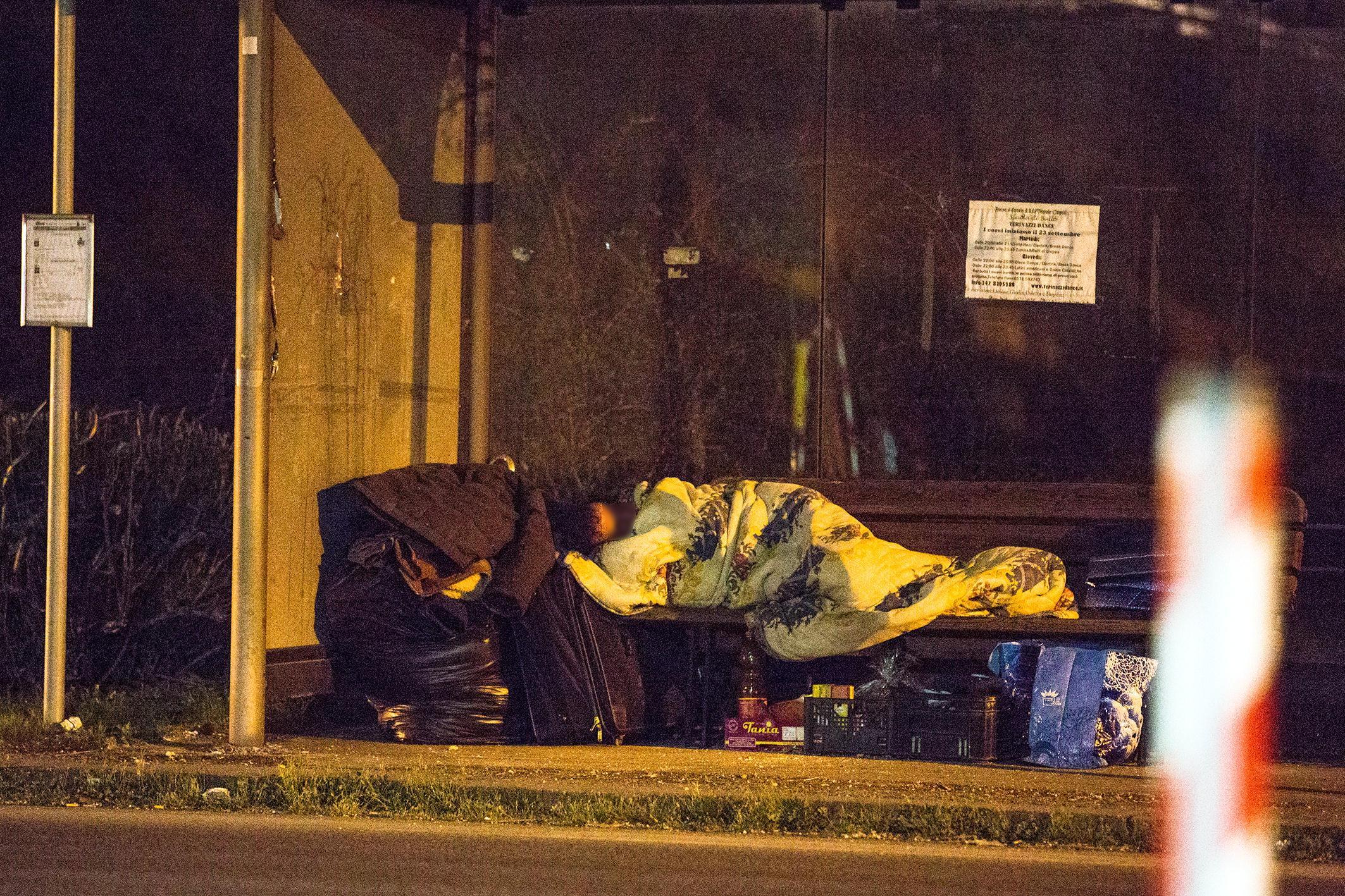 Un clochard dorme ad una fermata dell'autobus (foto d'archivio)