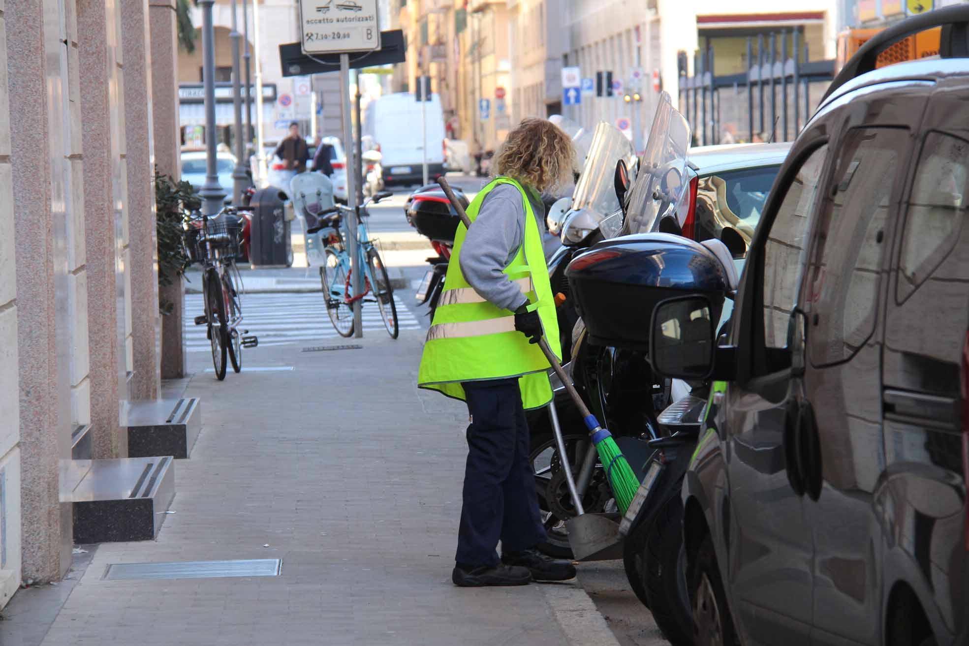 Una dipendente Cooplat mentre spazza la strada