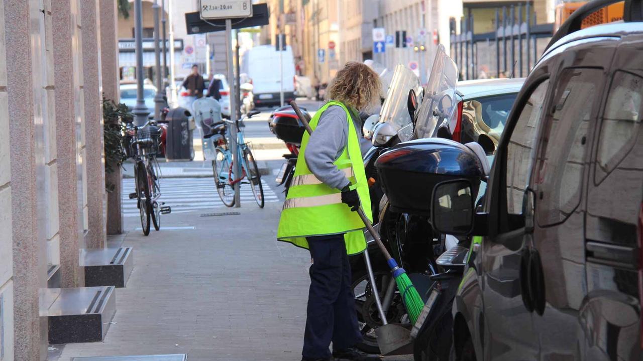 Una dipendente Cooplat mentre spazza la strada