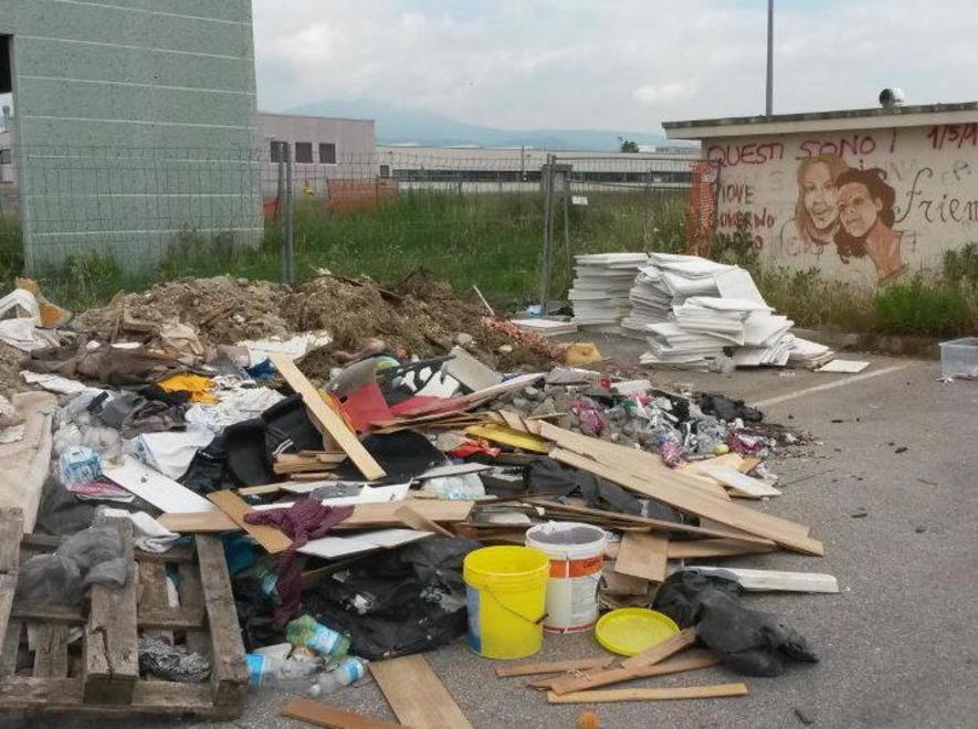 Rifiuti abbandonati tra erba e degrado 