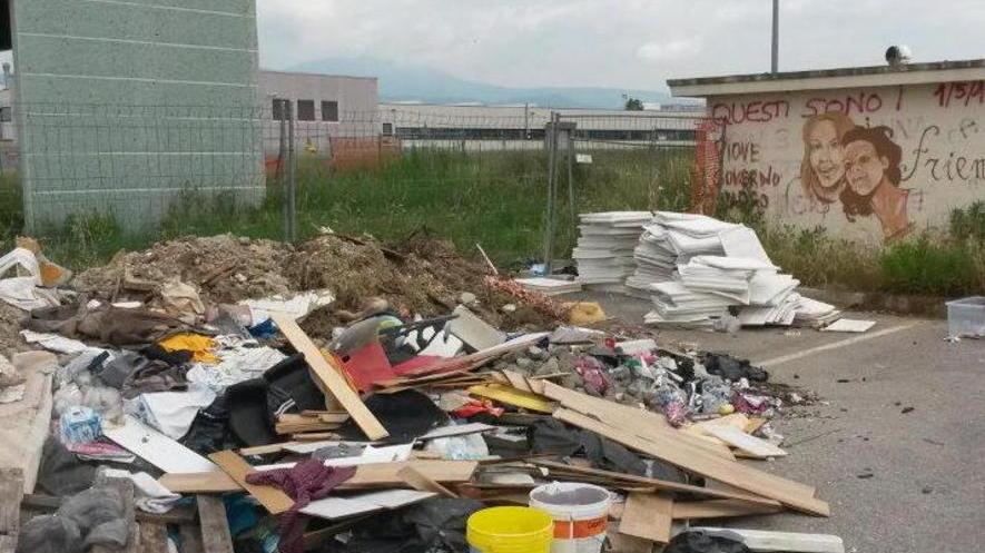 Rifiuti abbandonati tra erba e degrado