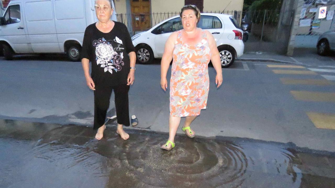 Due residenti mostrano l'acqua che sgorga dal tubo rotto (foto Batavia)