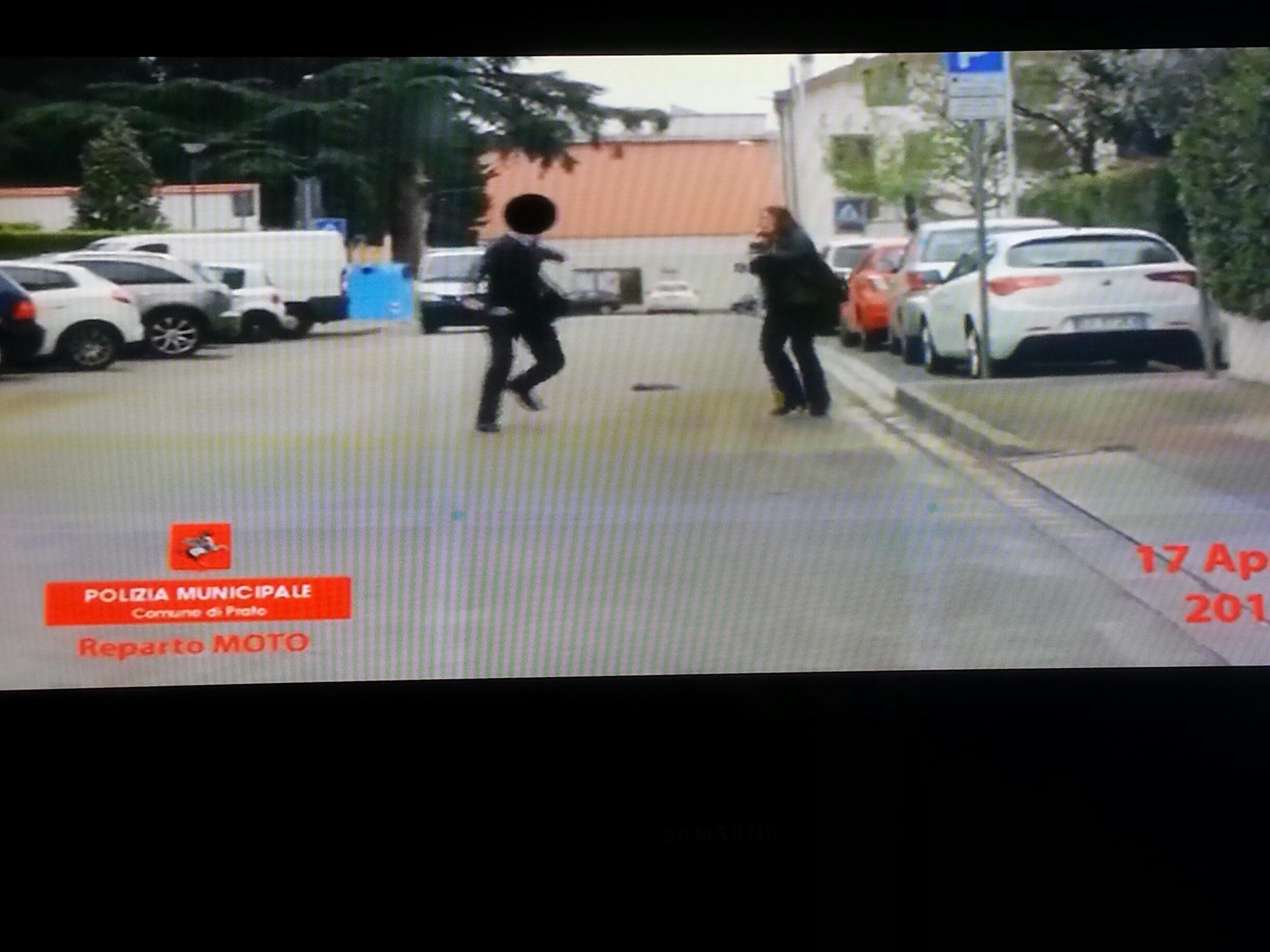 Nel fotogramma del video si vede il finto cieco mentre scansa il foulard lasciato cadere dalla vigilessa