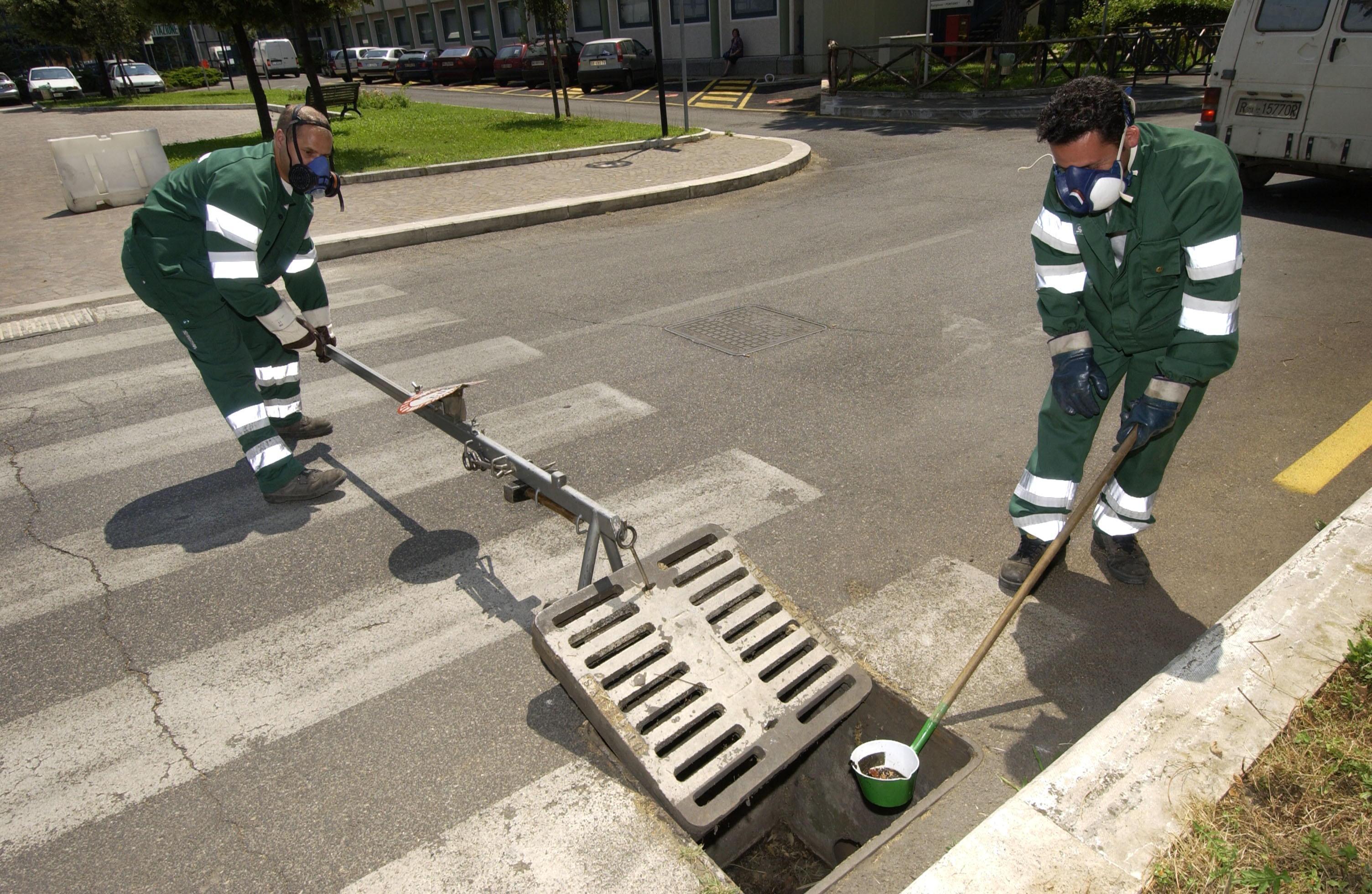 Operai durante la bonifica dei tombini dalle larve di zanzara