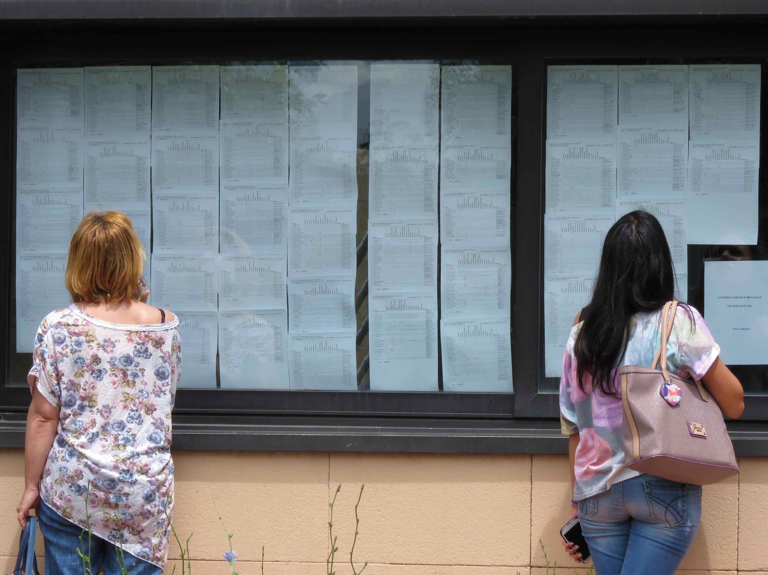 Due ragazze guardano i risultati scolastici sulle bacheche (foto Batavia)