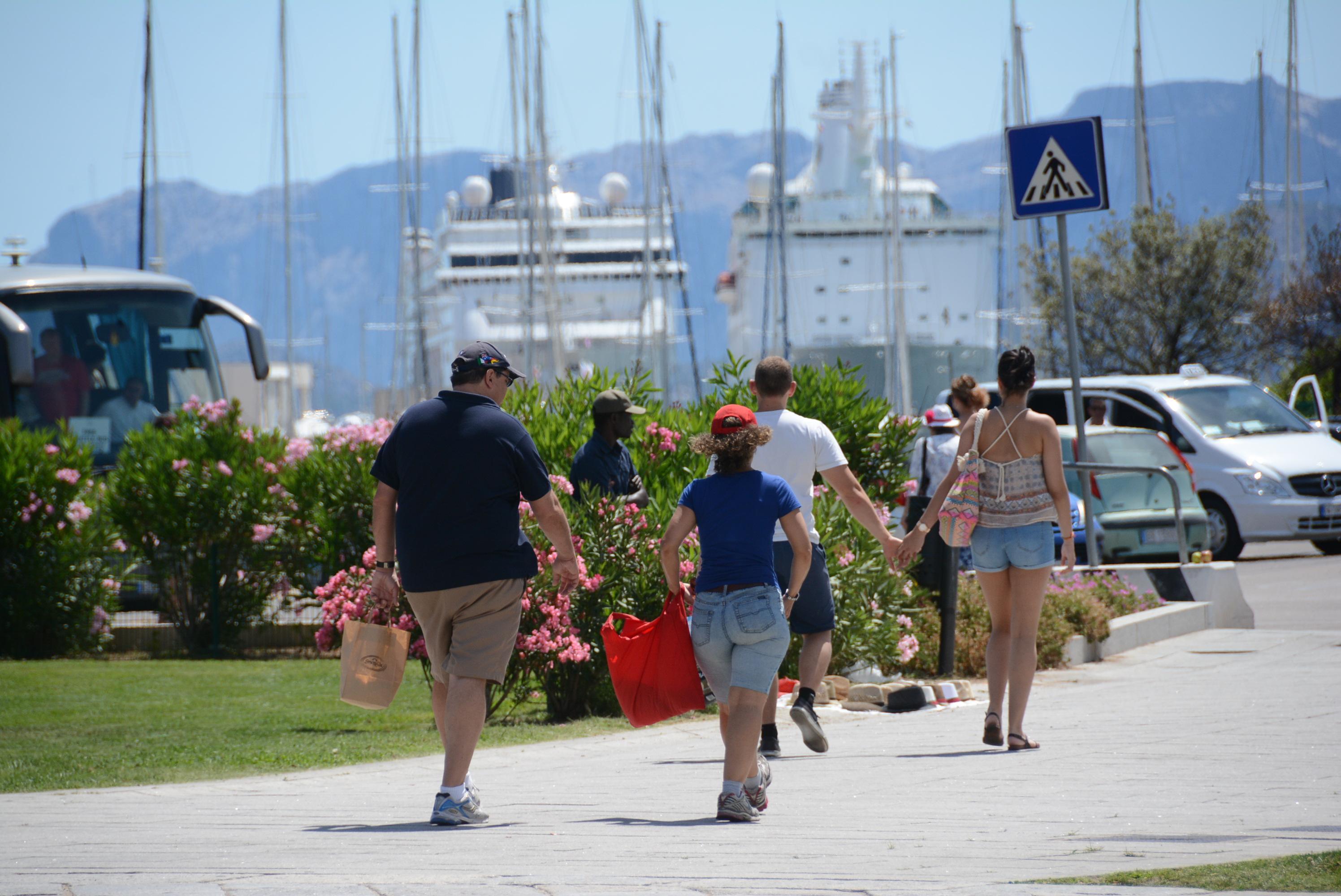 Crocieristi e, sullo sfondo, le due navi approdate all'Isola Bianca
