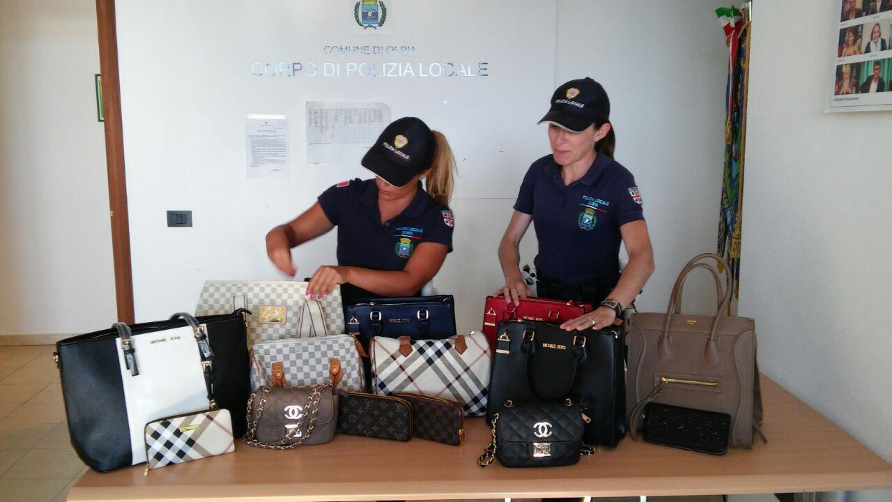 La polizia locale mostra le borse sequestrate in spiaggia 