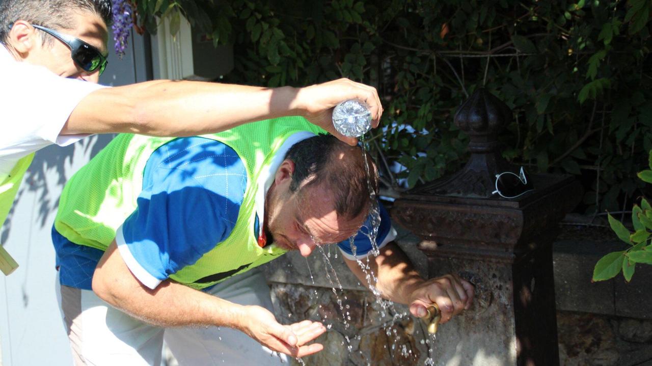 Un signore si bagna la testa a una fontana