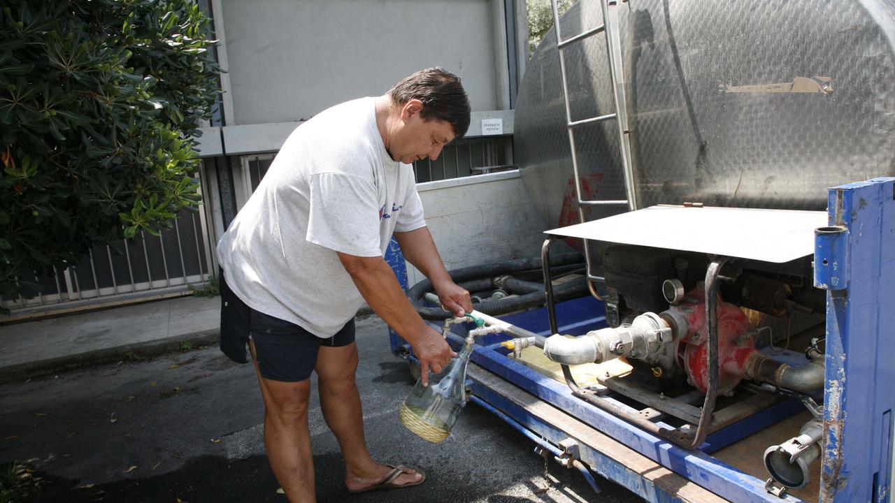 Un cittadino si rifornisce di acqua da un'autocisterna