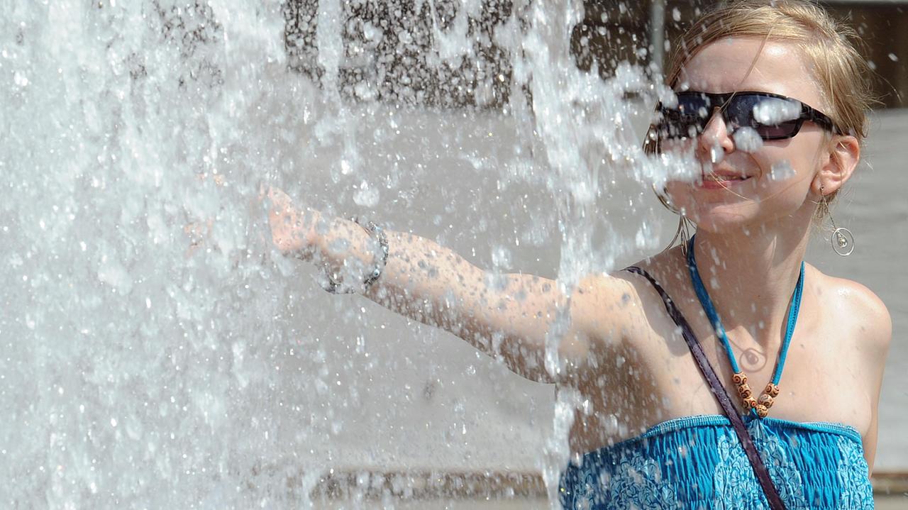 Una ragazza cerca refrigerio in una fontana