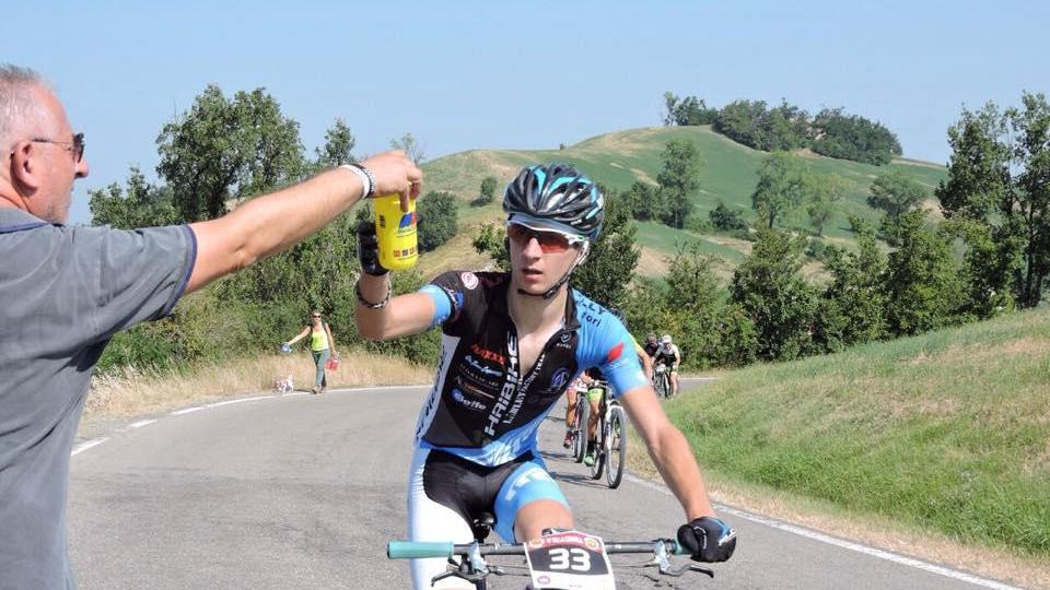 Simone Pardini durante una corsa mentre riceve la borraccia dal babbo Roberto