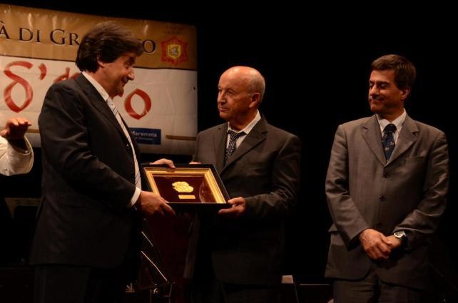 Il presidente della Pro loco Umberto Carini consegna il Grifone d'Oro a Irio Tommasini. A destra il sindaco Emilio Bonifazi (foto Agenzia Bf)