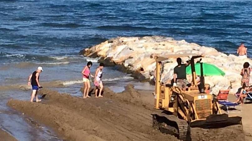 Cantiere volante in spiaggia una ruspa tra i bagnanti