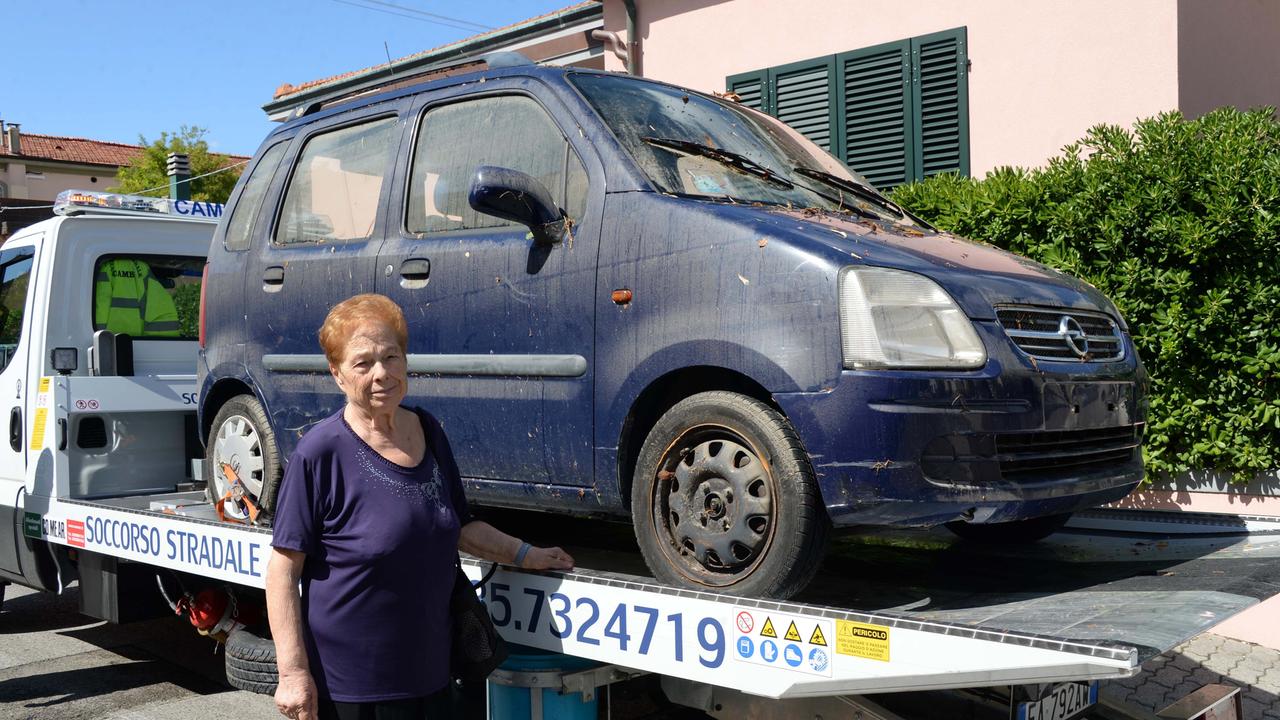 L'anziana accanto all'auto recuperata dal sottopassaggio (Foto Silvi)
