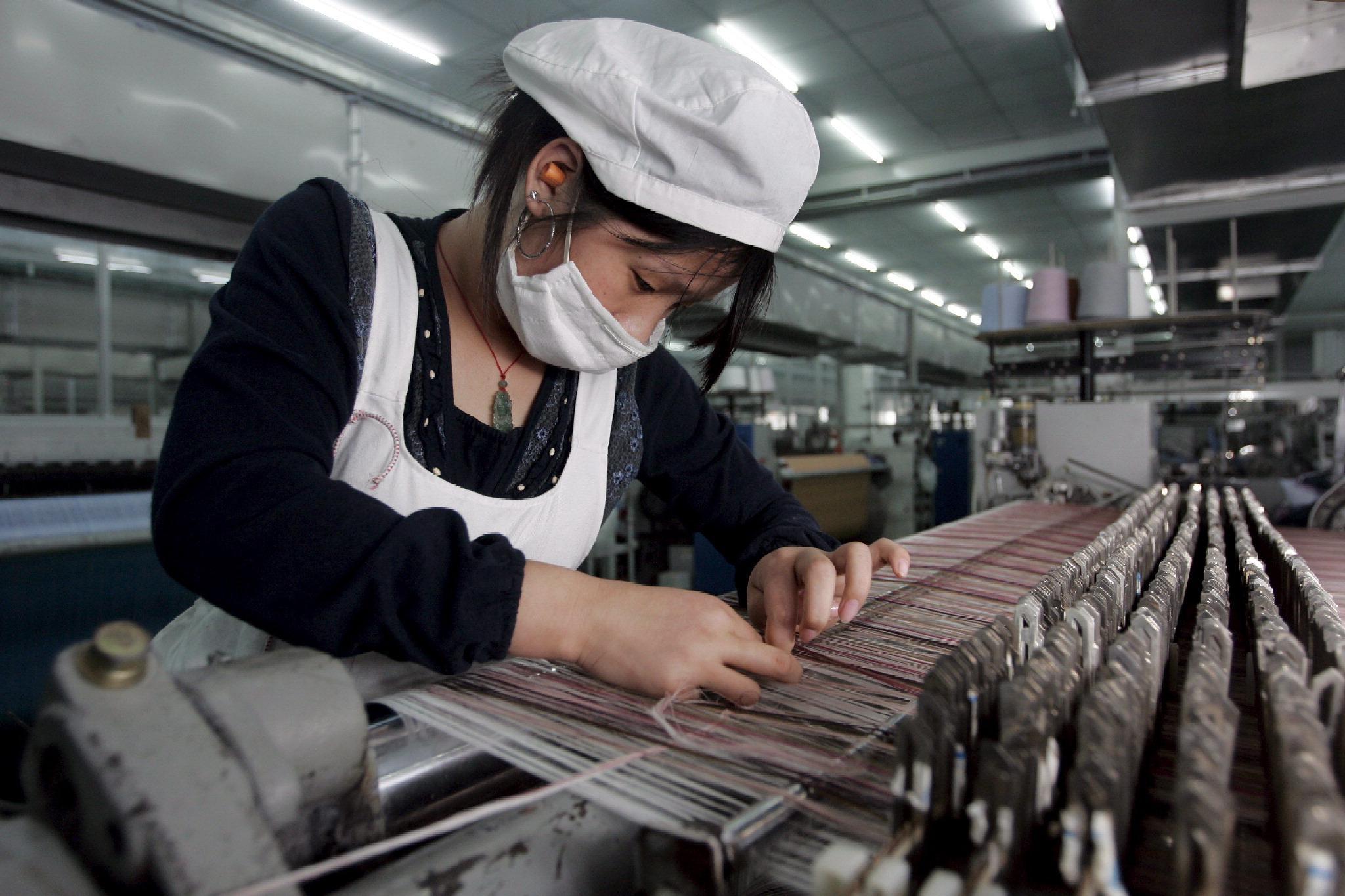 Un'operaia cinese al lavoro in una fabbrica tessile (foto d'archivio)